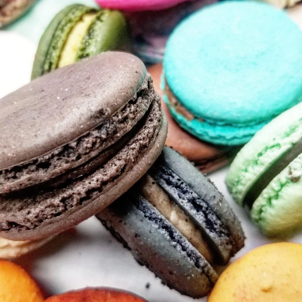 Assorted macarons in chocolate, teal, green and pink