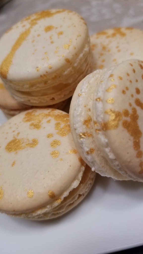 Vanilla macarons with gold flecks on a white plate