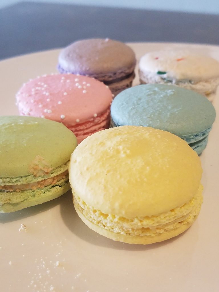 Pastel macarons in yellow, green, pink, blue and lavender on a plate