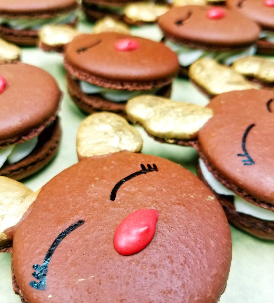Chocolate reindeer macarons with red noses and gold antlers for the holidays