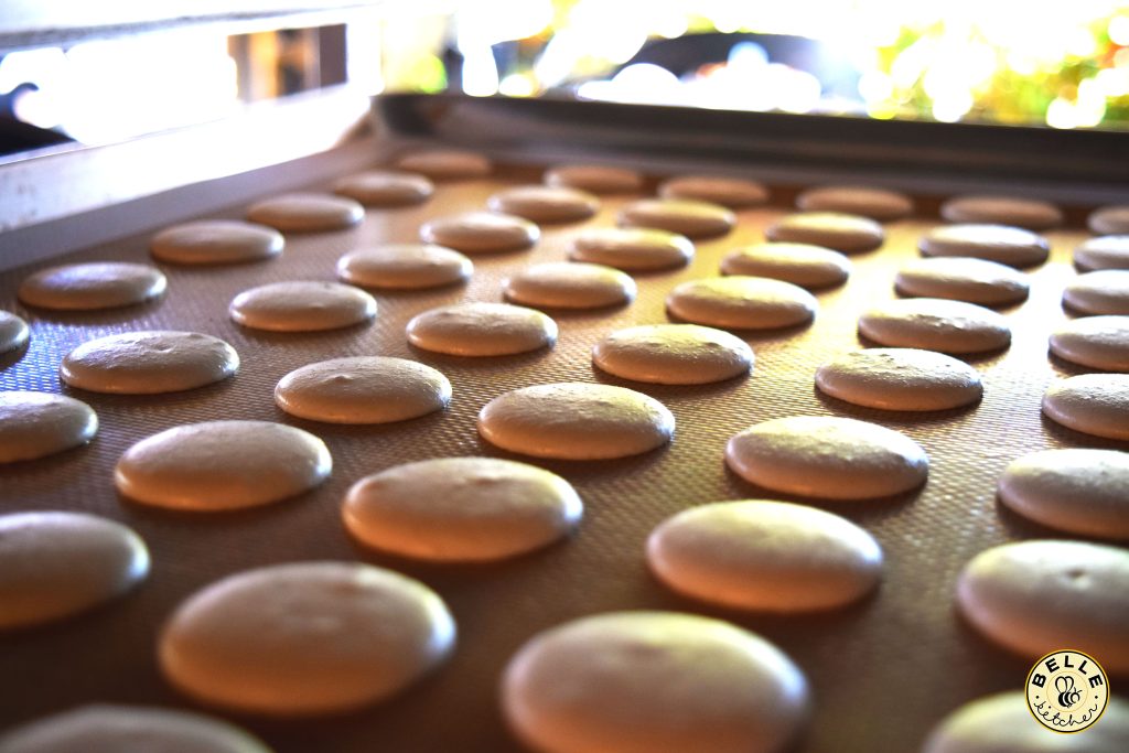 A baking tray of smooth chocolate macaron shells
