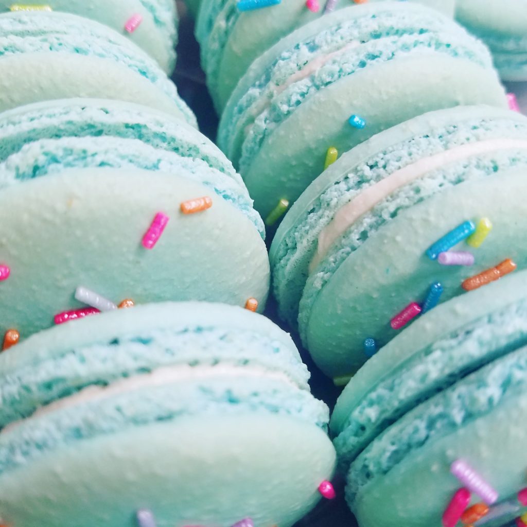 Turquoise macarons topped with rainbow sprinkles